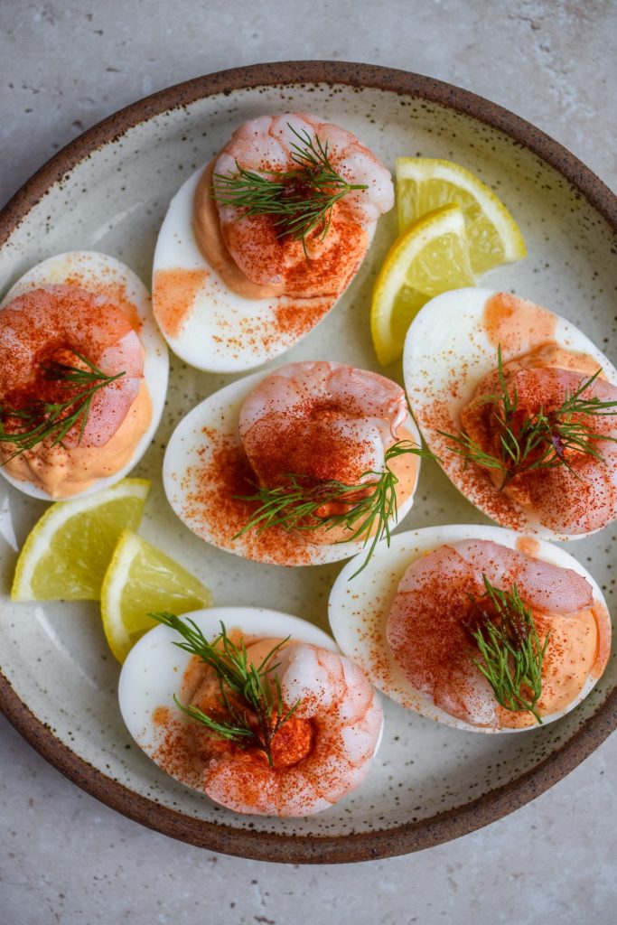Devilled eggs with king prawns and Marie Rose sauce on a stoneware plate.