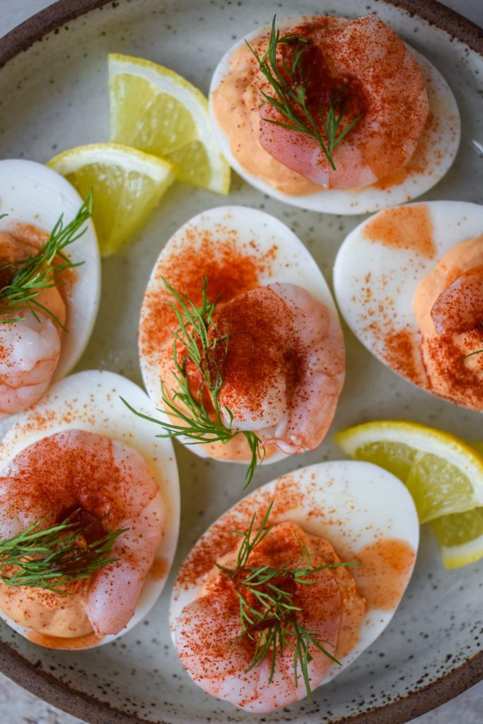 Close up of prawn cocktail devilled eggs with lemon wedges.