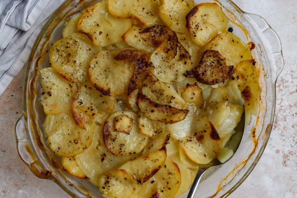 Close up of a dish of cooked sliced potatoes.