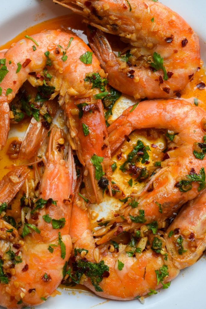Close up of king prawns cooked in garlic, chilli and parsley.