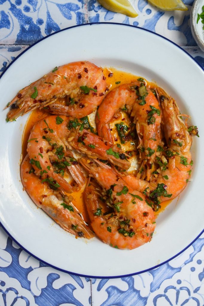 Prawns in chilli and garlic oil on a white and blue plate.