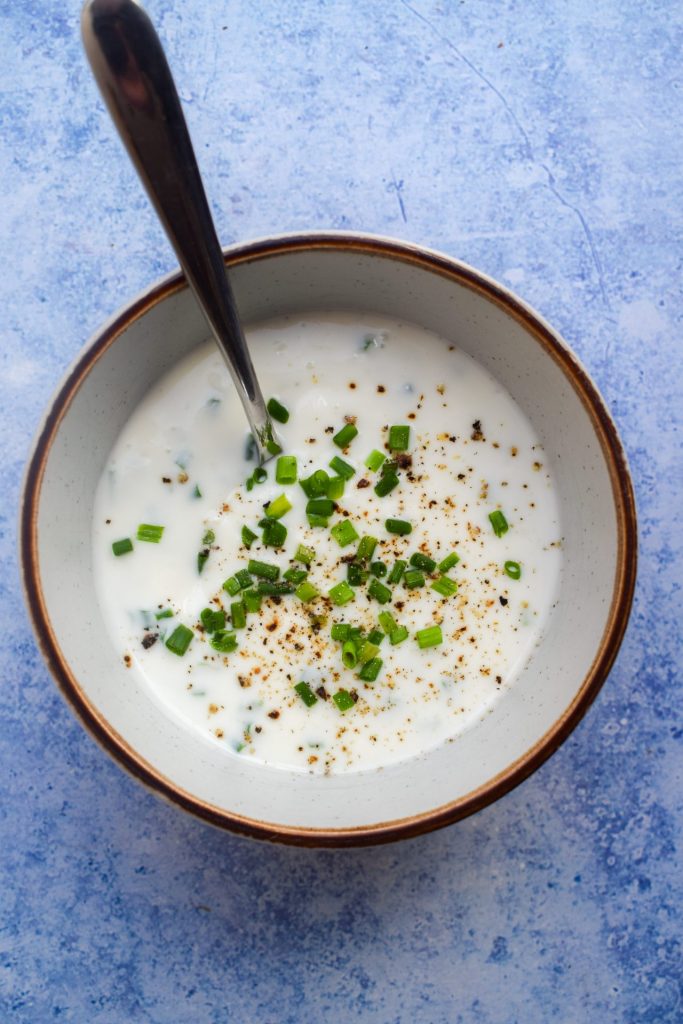 Bowl of buttermilk ranch dressing on a blue background.