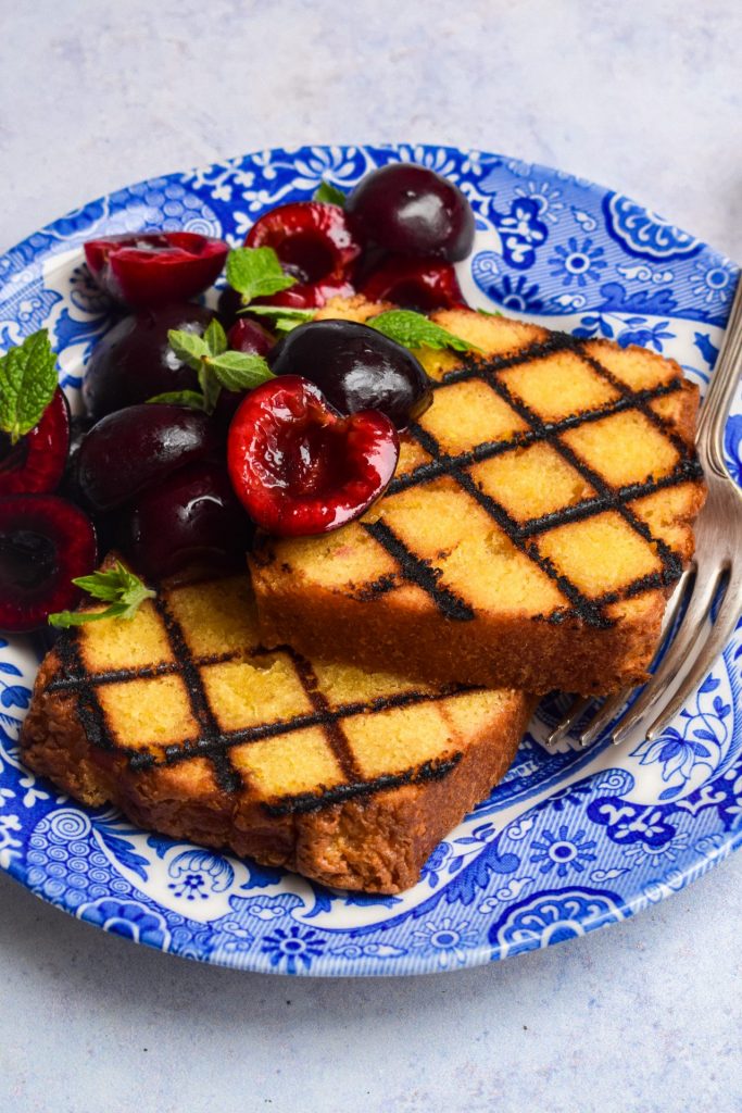 Barbecued cake with fresh cherries on a blue plate.