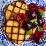 Grilled marzipan cake with fresh cherries on a blue plate.
