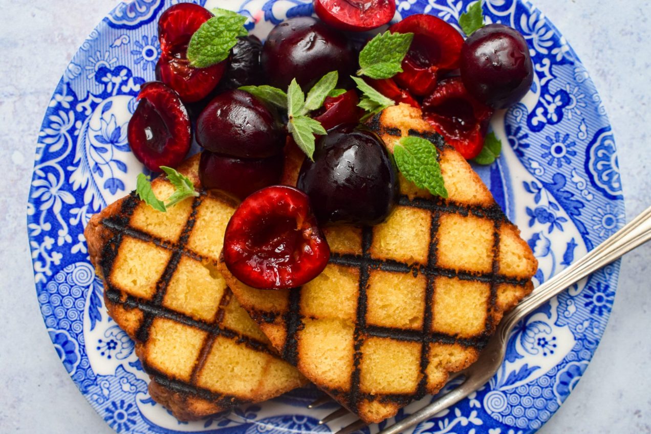 Grilled slices of cake topped with fresh cherries and mint.