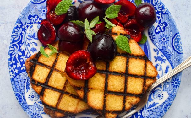 Grilled slices of cake topped with fresh cherries and mint.