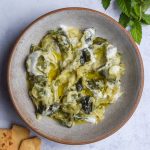 Bowl of courgette and yogurt dip on a light blue background.
