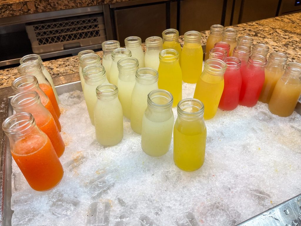 Fresh juices on ice in small milk bottles.