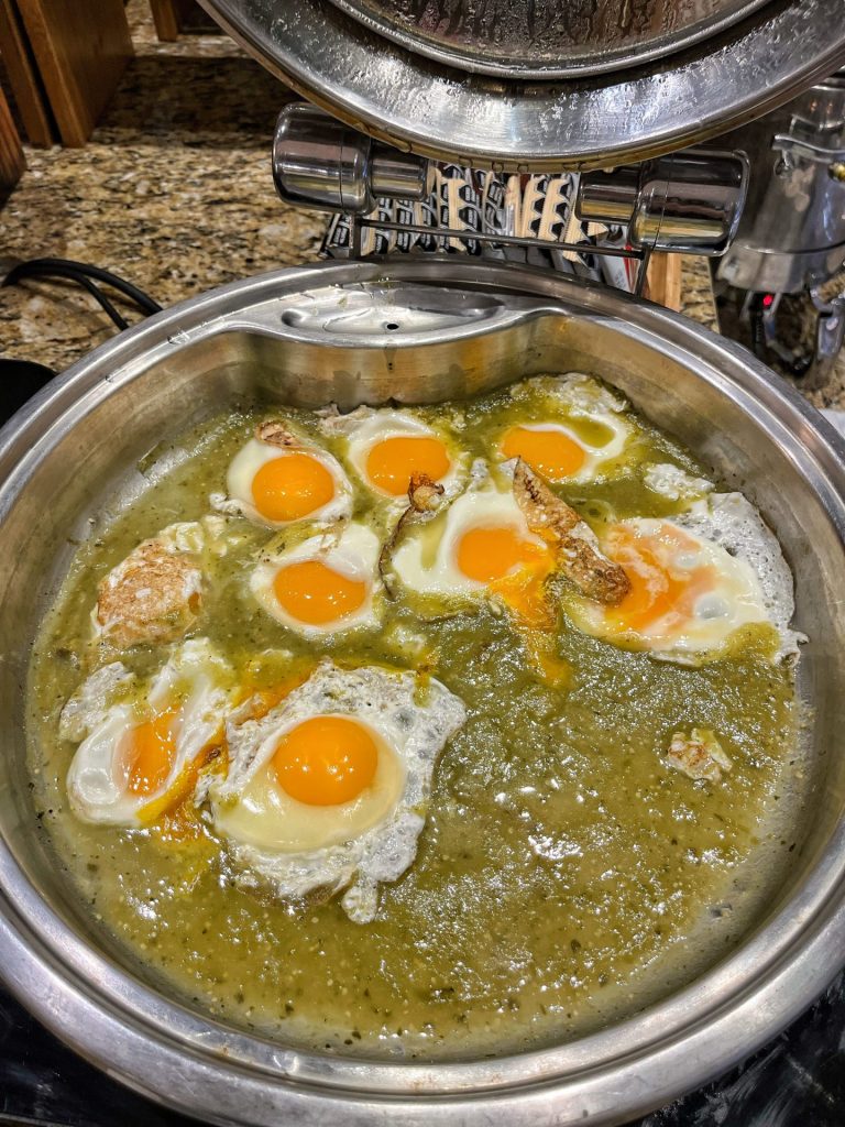 Catering dish of fried eggs in green sauce.