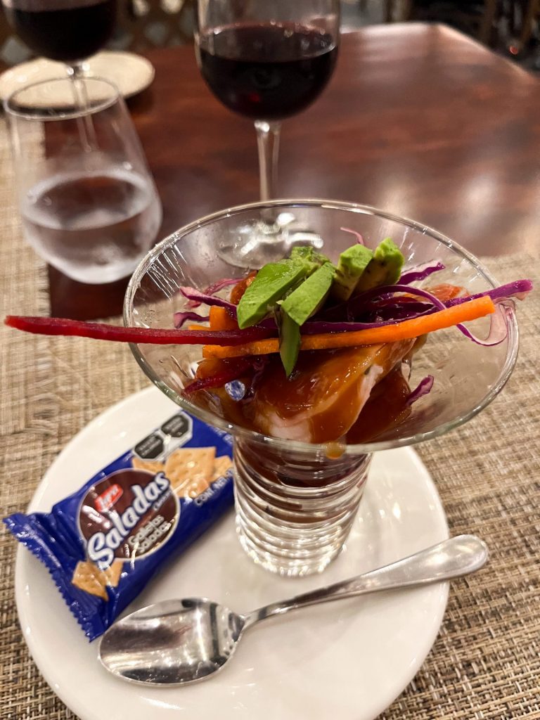 Glass of Mexican shrimp cocktail with a packet of crackers on the side.