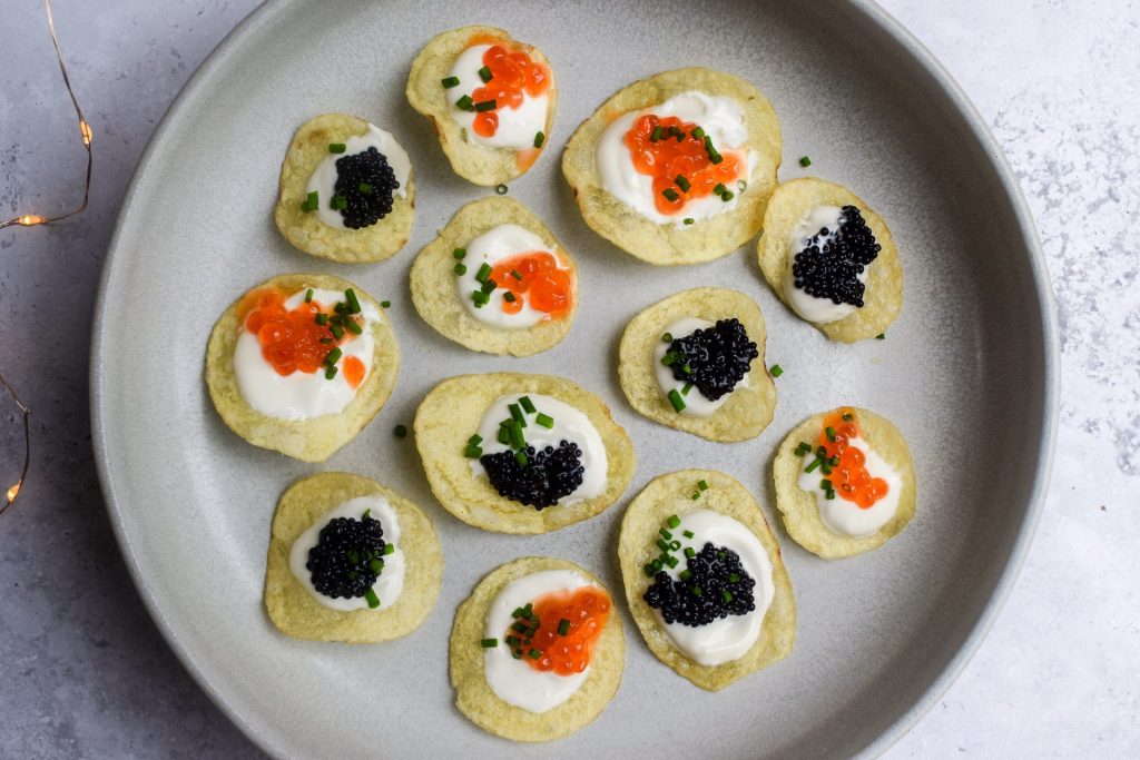 A grey plate of crisps topped with sour cream and black and orange caviar.