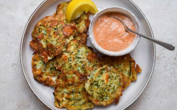 Stone plate of courgette fritters with a bowl of yogurt dip.