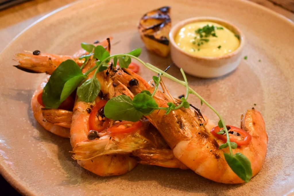 Shell on prawns with sliced chilli and pea shoots.