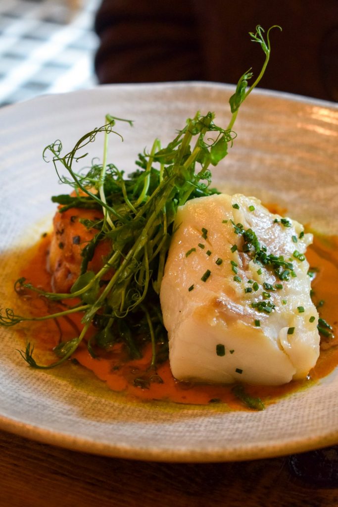 Cod with pea shoots on a plate of bisque