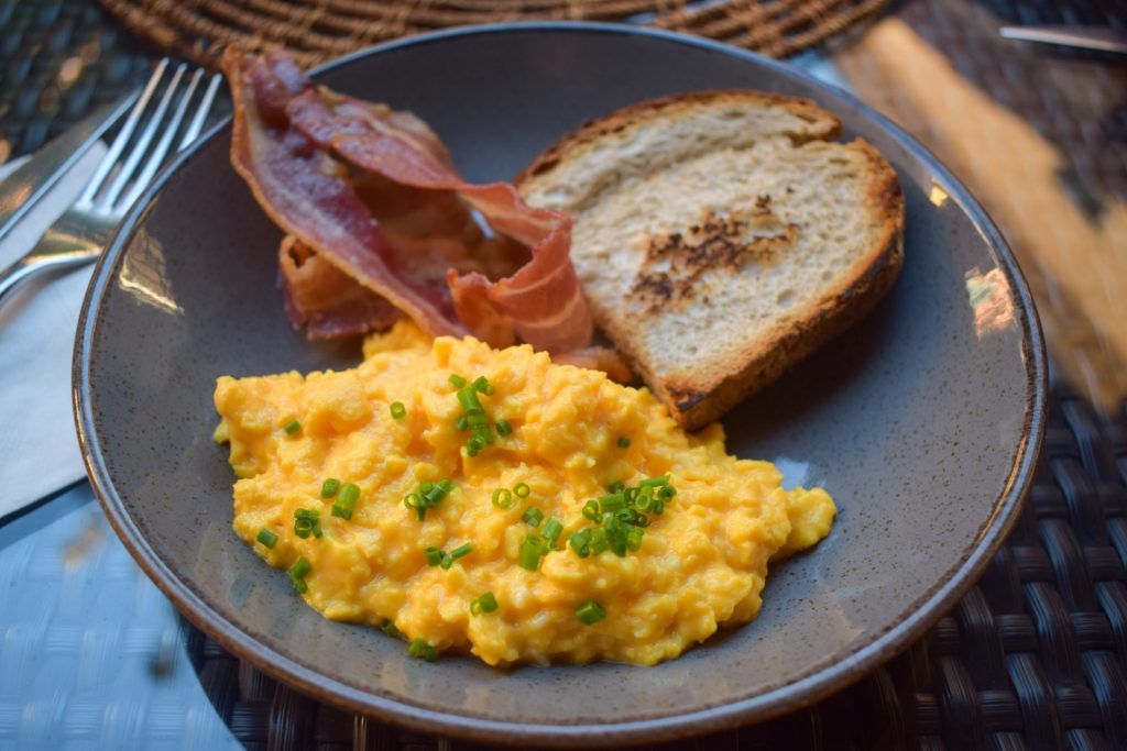 Plate of scrambled eggs, toast and bacon.