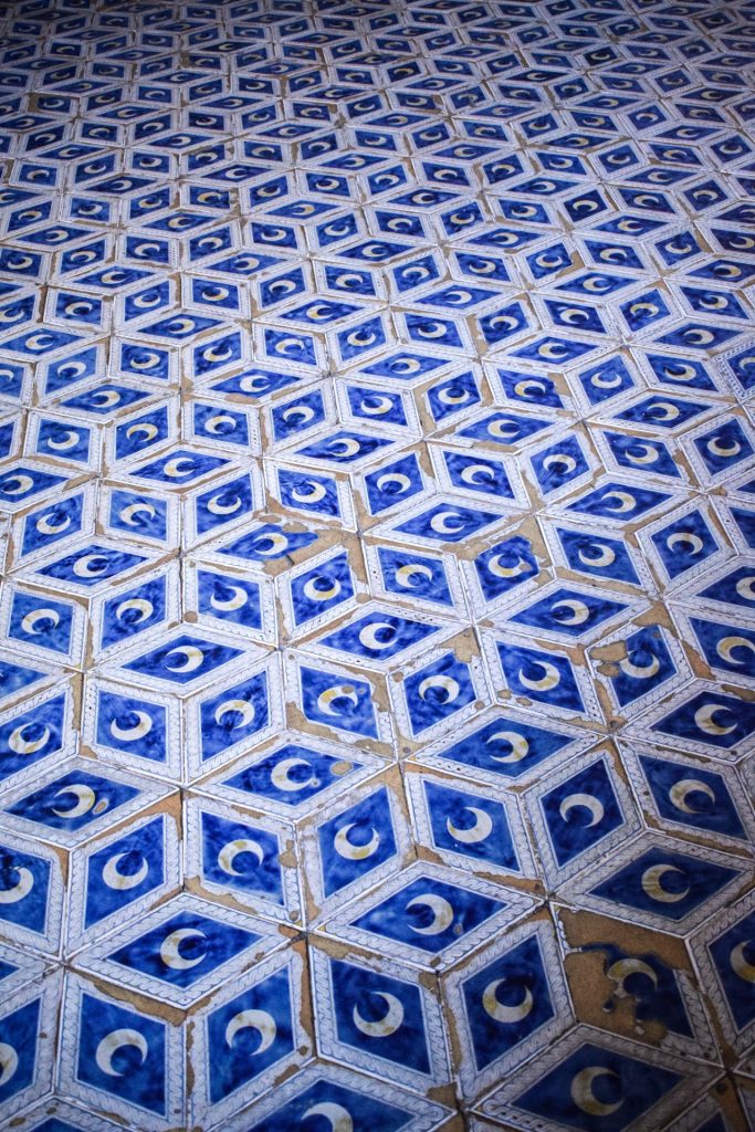 Blue and white diamond mosaic floor decorated with crescent moons on each tile.