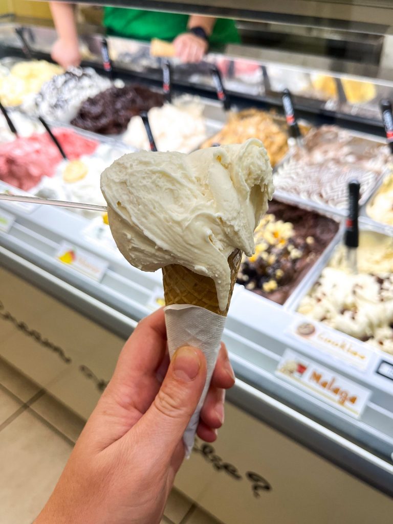 Hand holding a scoop of pear gelato in a waffle cone