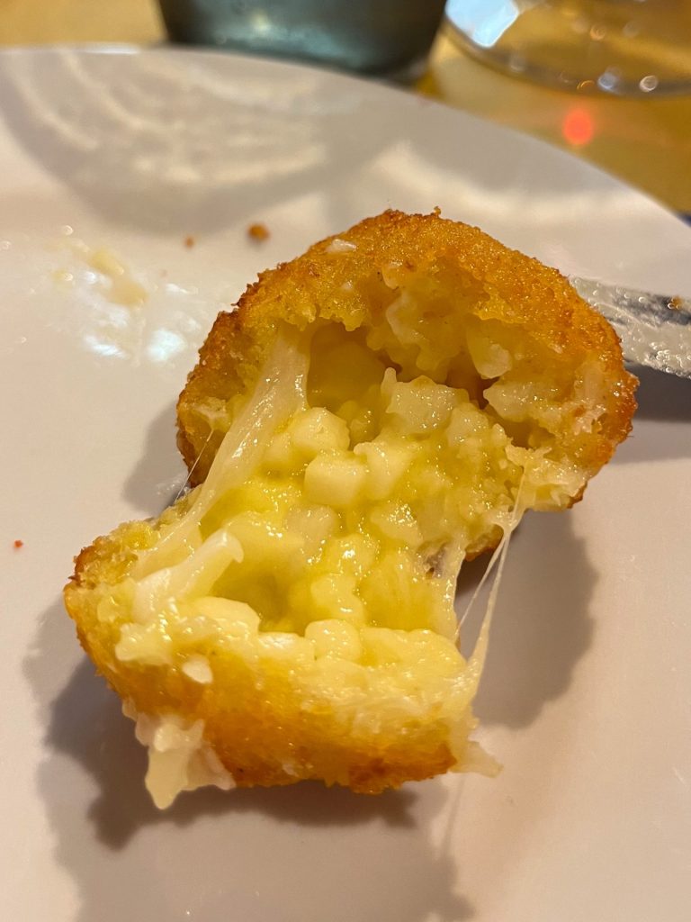 A pecorino fritter cut in half to show the melted cheese filling.