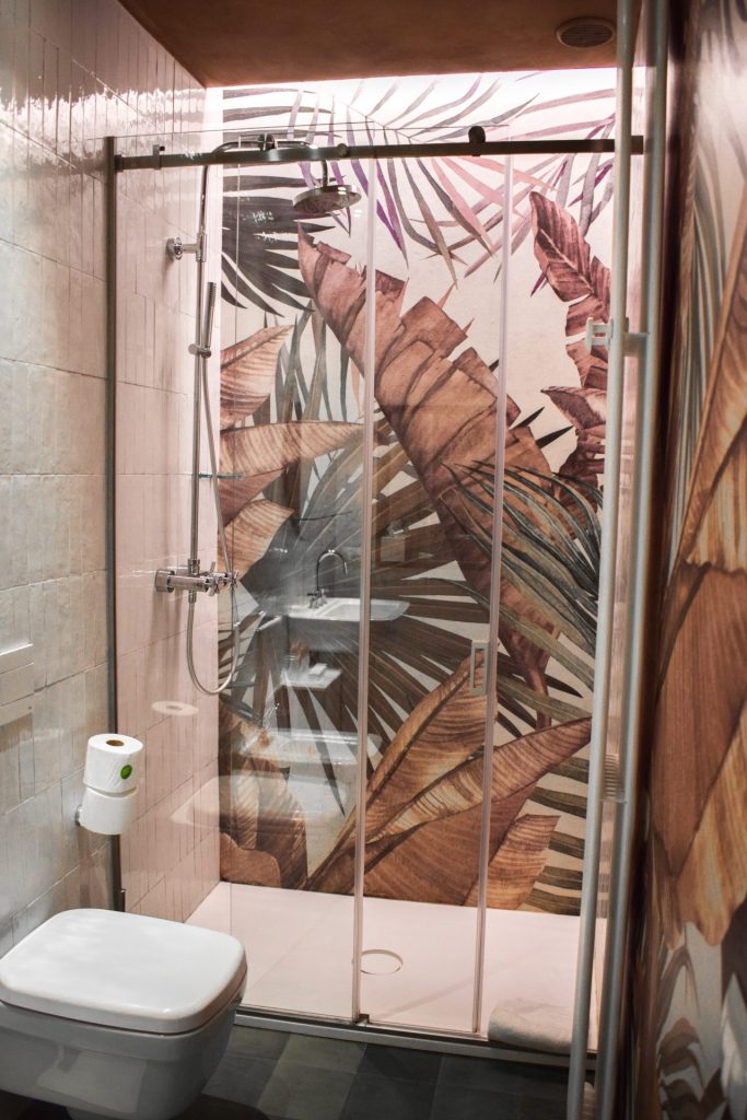 A tropical leaves painted shower in a hotel bathroom