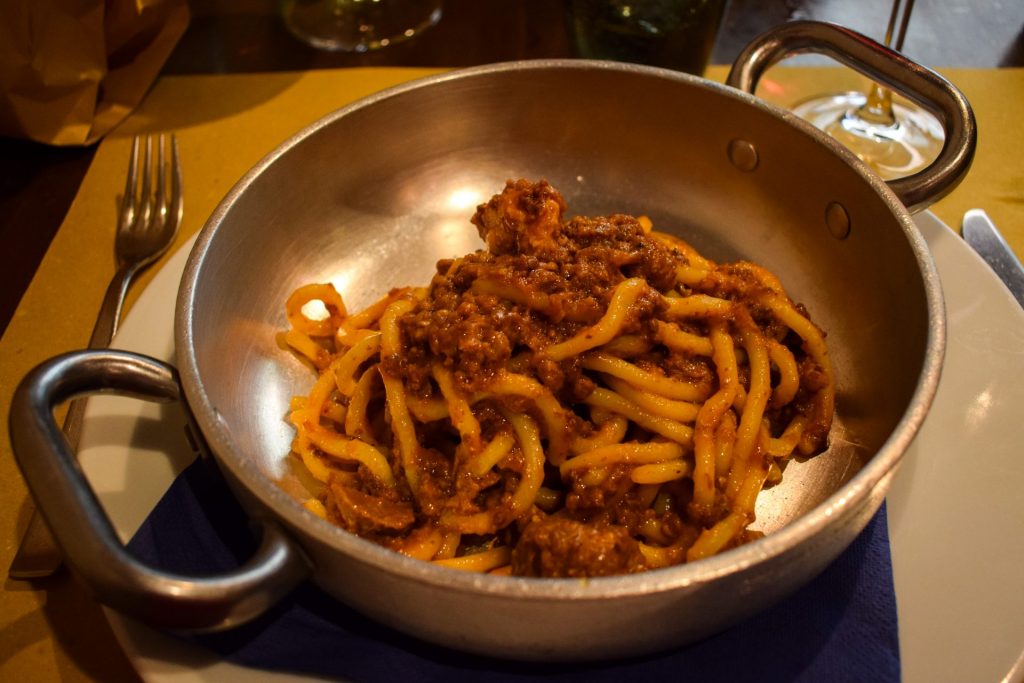 A metal dish of pici pasta with wild boar ragu.