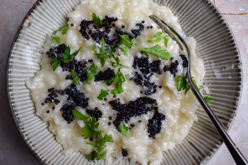 Close up of a champagne and caviar risotto with chopped parsley.