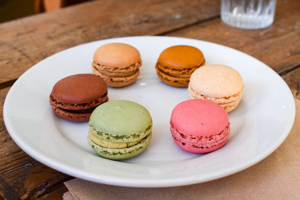 Plate of pastel macarons on a wooden table.