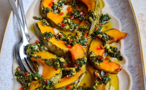 Close up of a platter of squash wedges topped with salsa verde and chopped chilli.