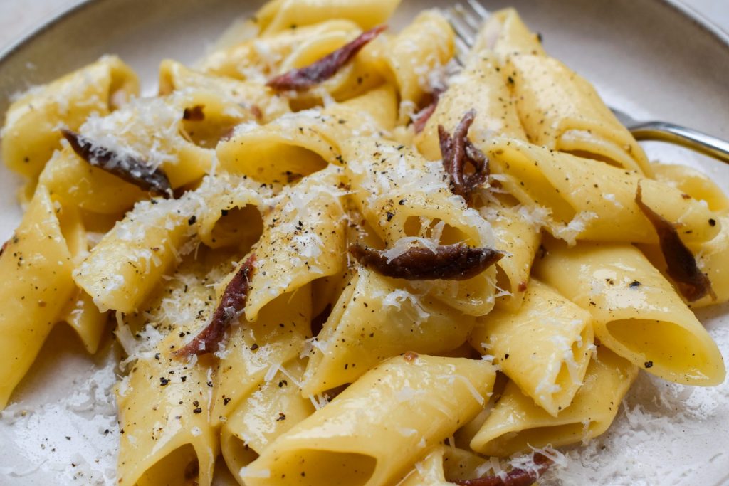 Pasta carbonara made with anchovies and topped with grated cheese.