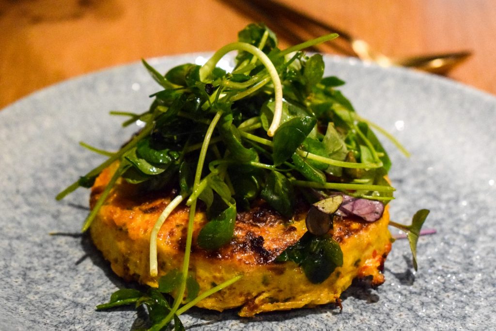 Spanish tortilla on a blue plate topped with a tangle of pea shoots.