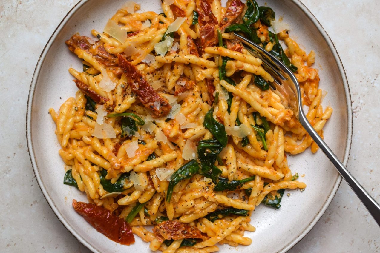 Tuscan Sun-dried Tomato and Spinach Pasta in a stone bowl with a fork.