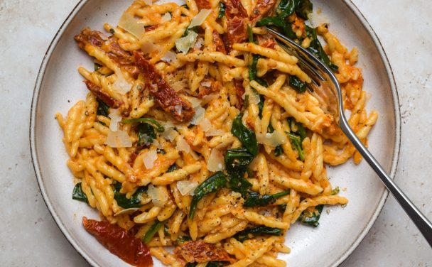 Tuscan Sun-dried Tomato and Spinach Pasta in a stone bowl with a fork.