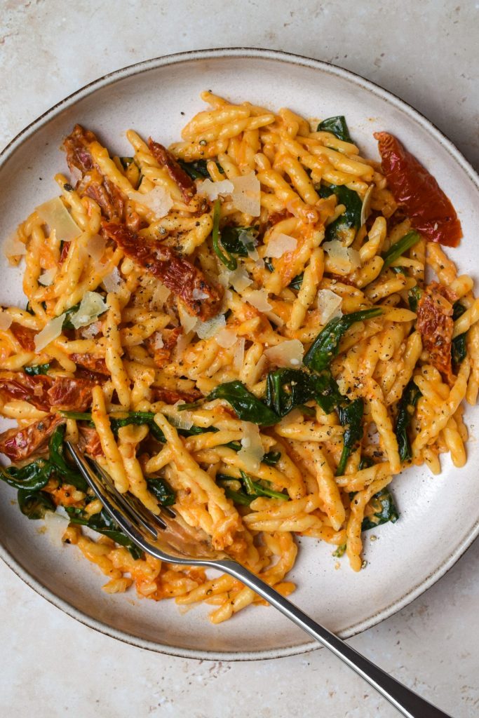 Creamy tomato pasta with spinach and parmesan in a stone bowl.
