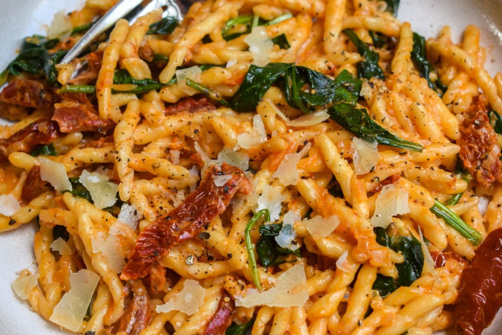 Tuscan Sun-dried Tomato and Spinach Pasta close up with shaved parmesan.