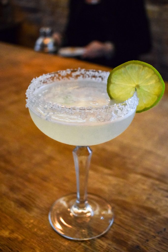 Margarita in a glass rimmed with salt and garnished with a lime wheel.
