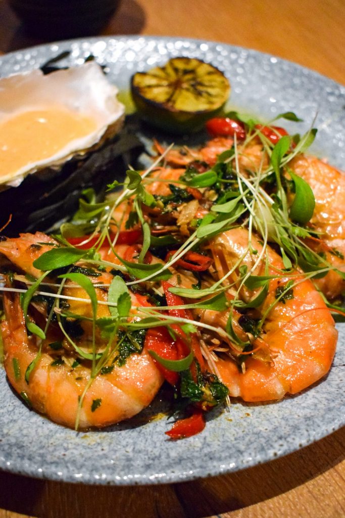 Prawns with chilli and garlic in their shells garnished with micro coriander. 