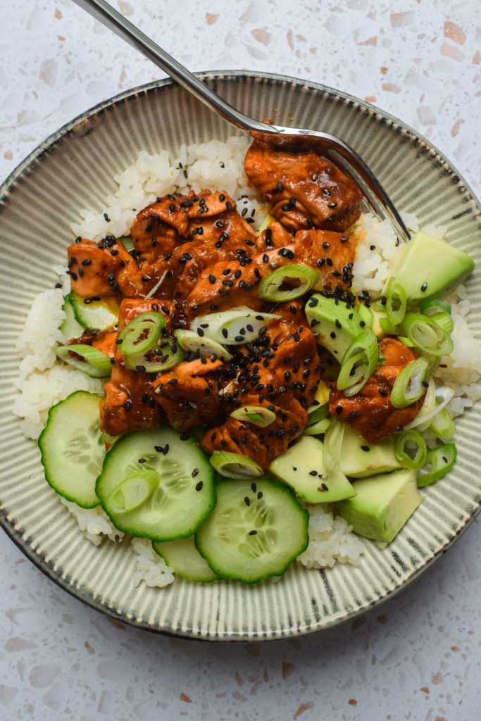 Spicy salmon and avocado rice bowl on the countertop.