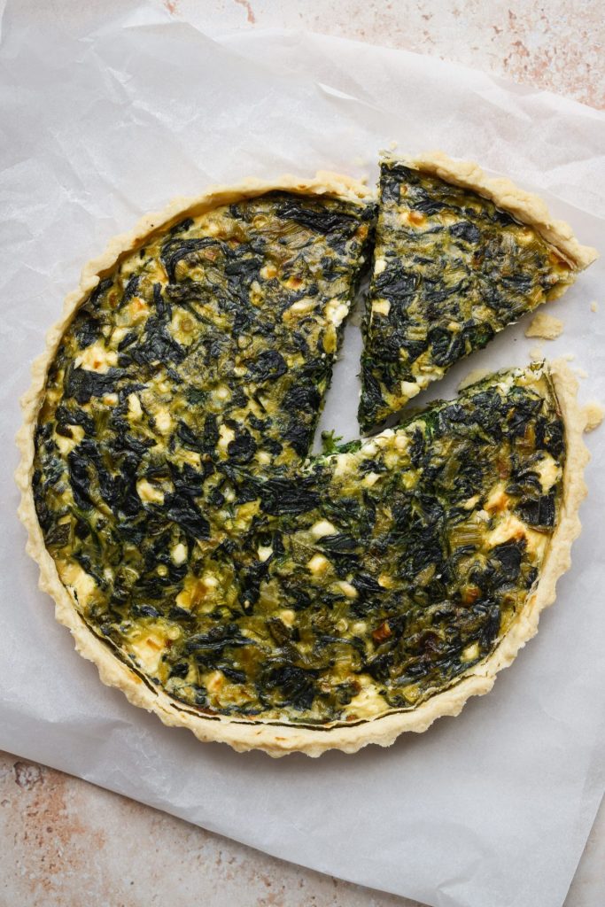 Spinach and feta tart with a slice being taken out.