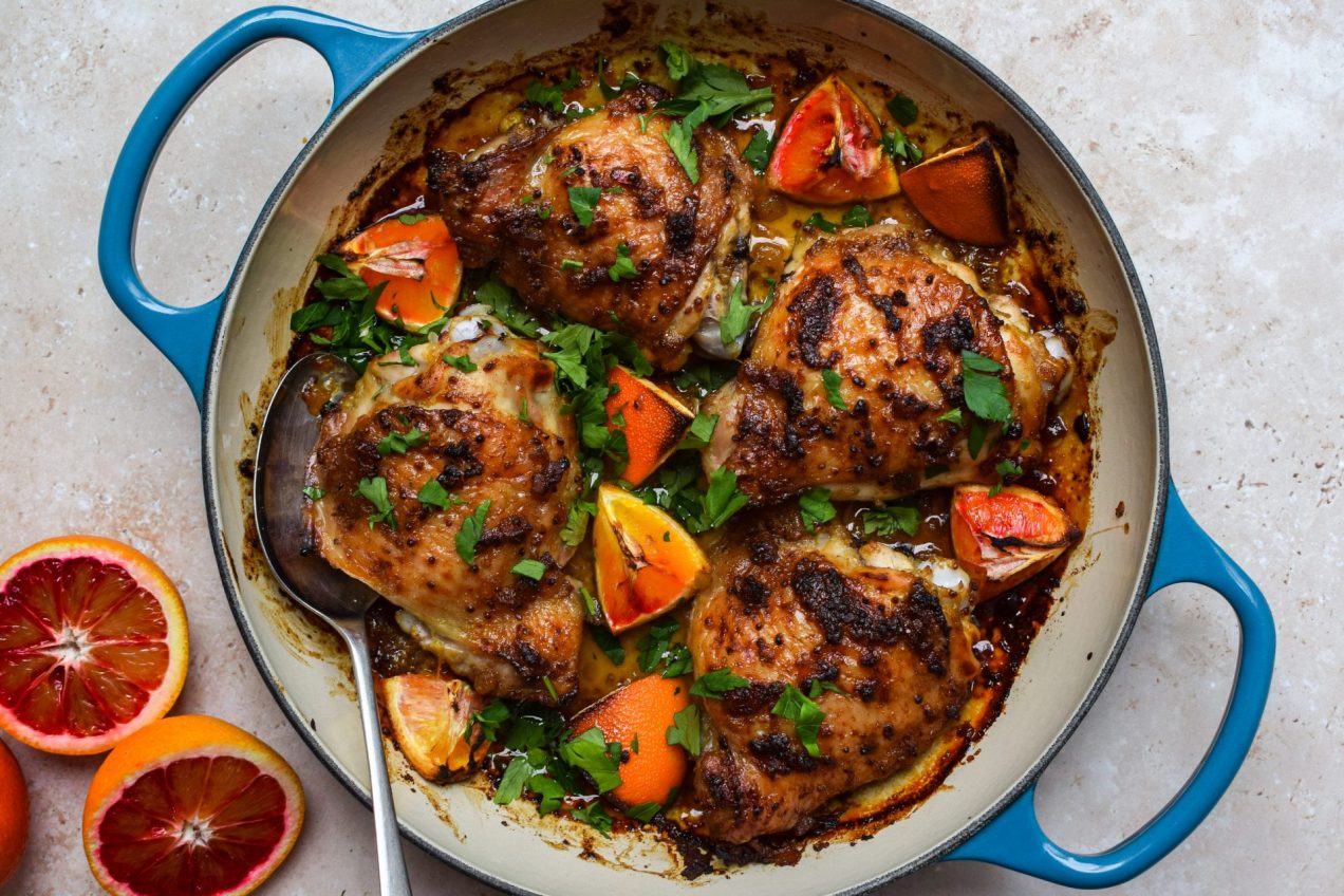 Dish of roasted chicken and blood orange pieces with sliced blood oranges pictured on the side.