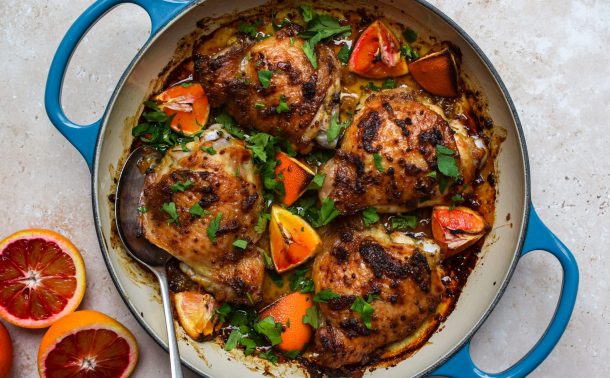 Dish of roasted chicken and blood orange pieces with sliced blood oranges pictured on the side.