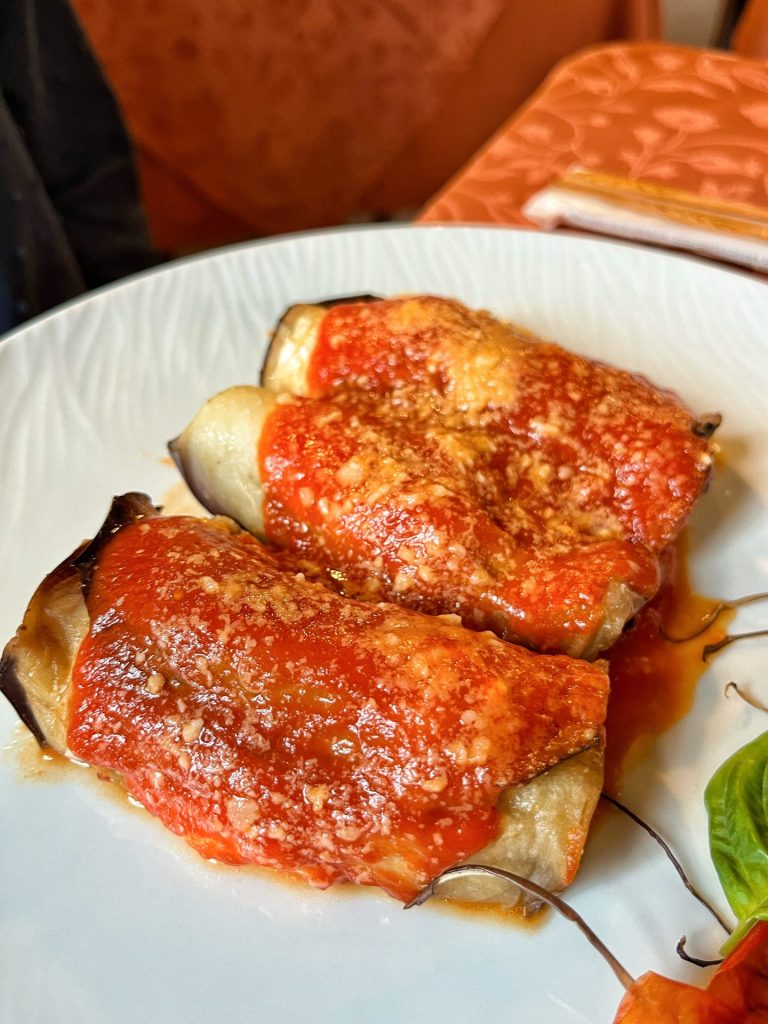 Aubergine ricotta rolls topped with tomato sauce and grated parmesan