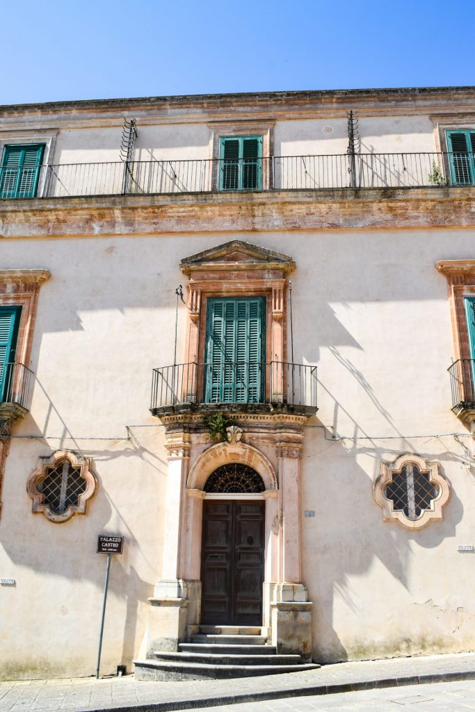 Palazzo facade with pale green shutters.