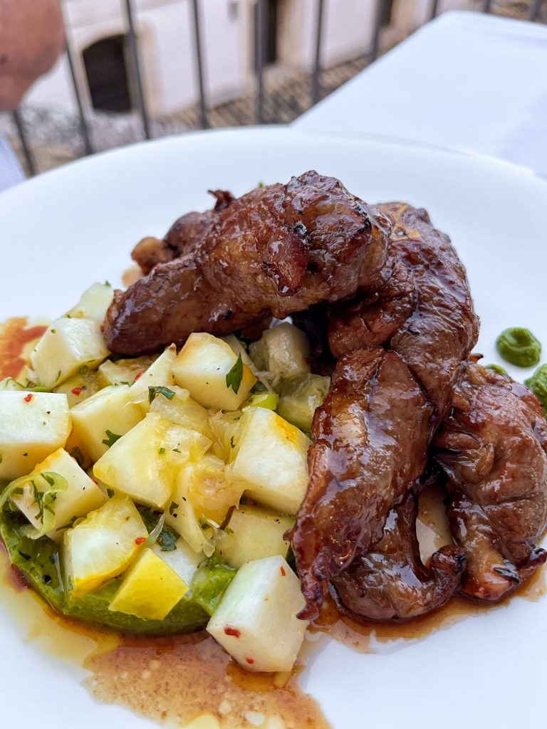 White plate of grilled lamb with a diced lemon rind salad.