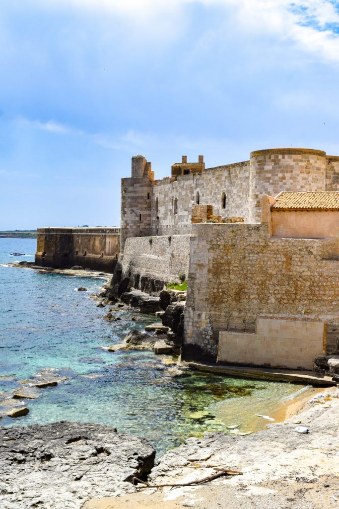 Side view of the Castello Maniace in Ortigia with the sea visible to one side.