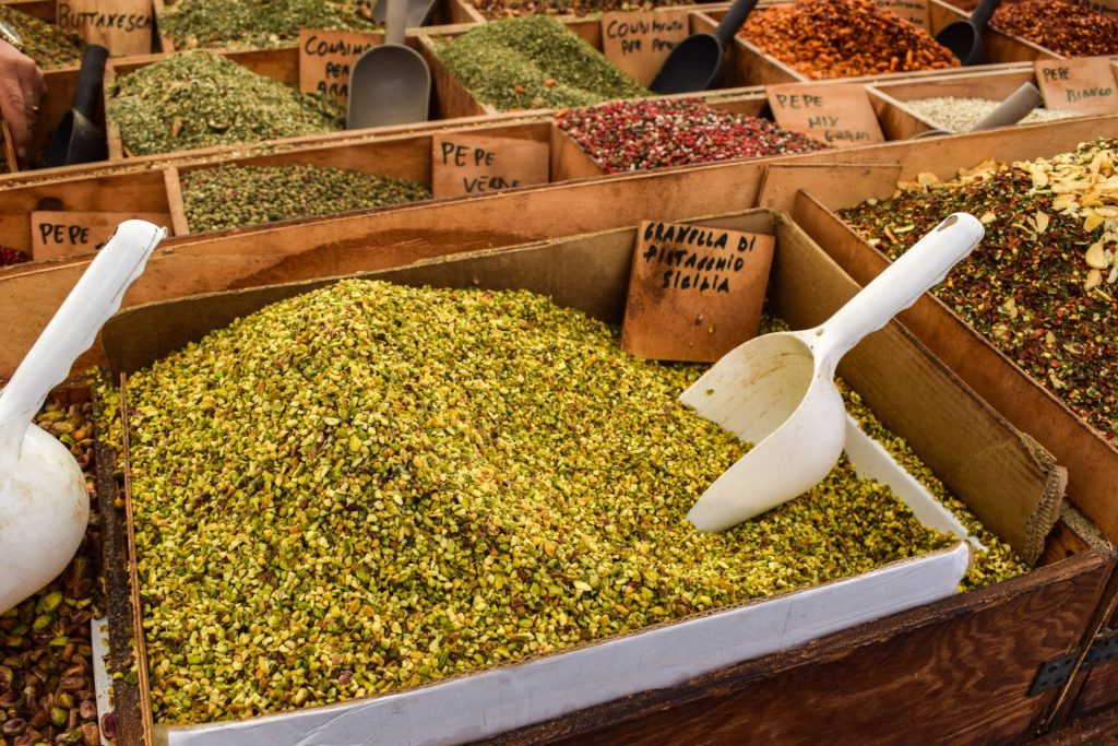 Tray of chopped pistachios with a scoop on a market stall.