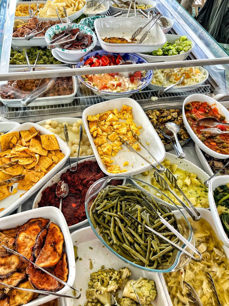 Open fridge filled with platters of Sicilian antipasti and apero salads