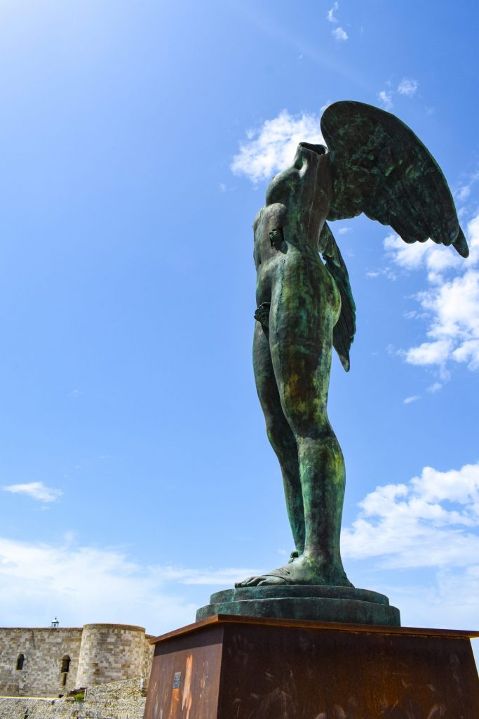 Mitoraj sculpture in Ortigia against a bright blue sky.