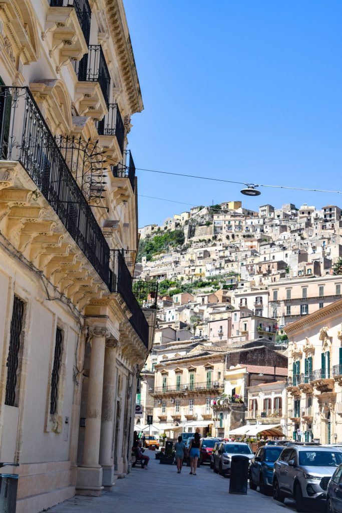 Street view of Modica showing the down rising up in the background.