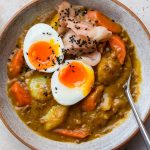 Bowl of Japanese lentil curry topped with a soft boiled egg, pickled ginger and black sesame seeds.