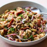 Bowl of tuna and white bean salad with a metal spoon.