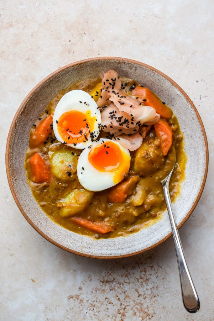 Overhead image of a bowl of Japanese lentil curry topped with a soft boiled egg.